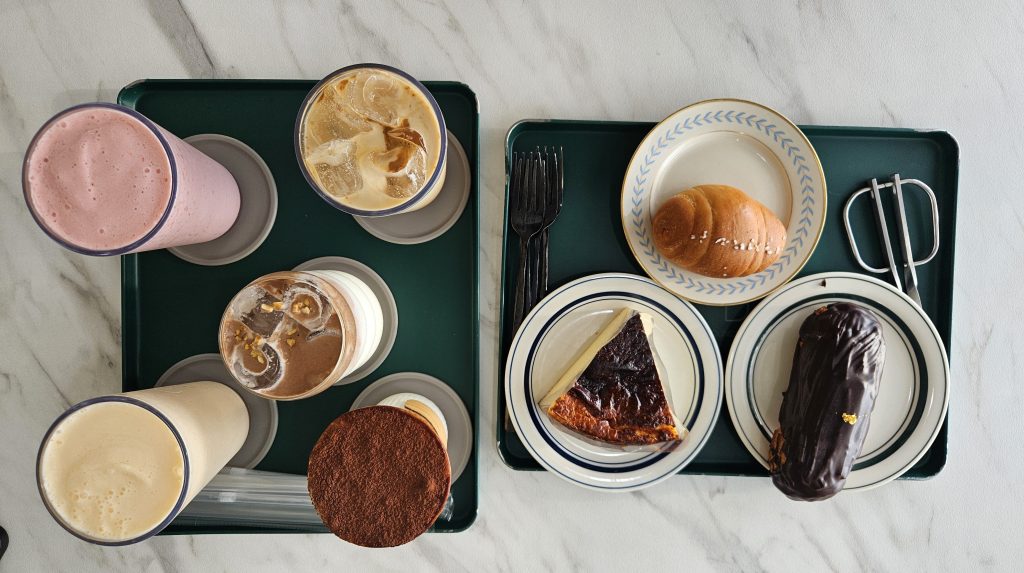 an overhead shot of a group of friends' cafe order. There are 3 pastries and 4 drinks. It looks super yummy and cozy!